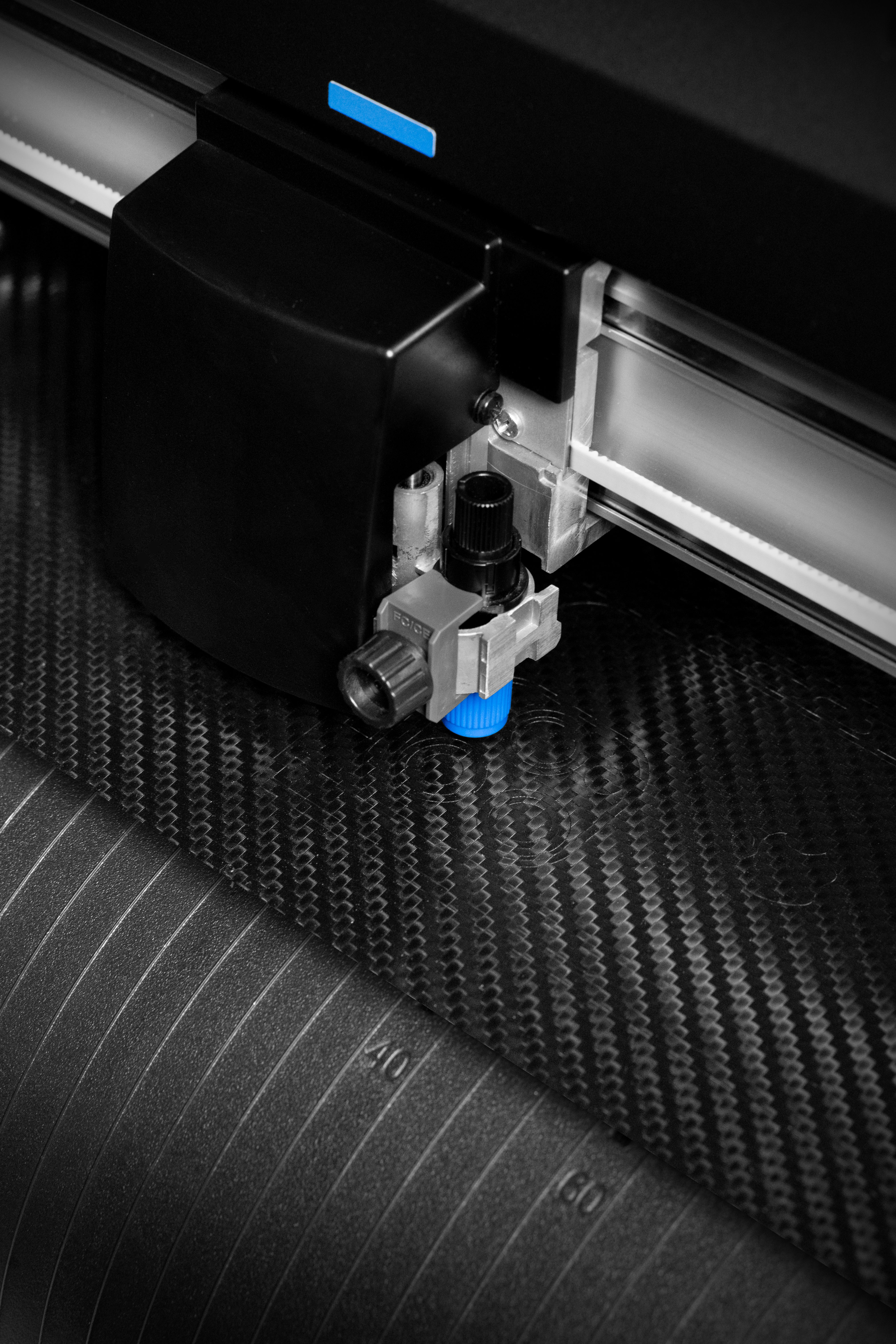 Close-up of a professional cutting plotter creating precision-cut vinyl skins from black carbon skin