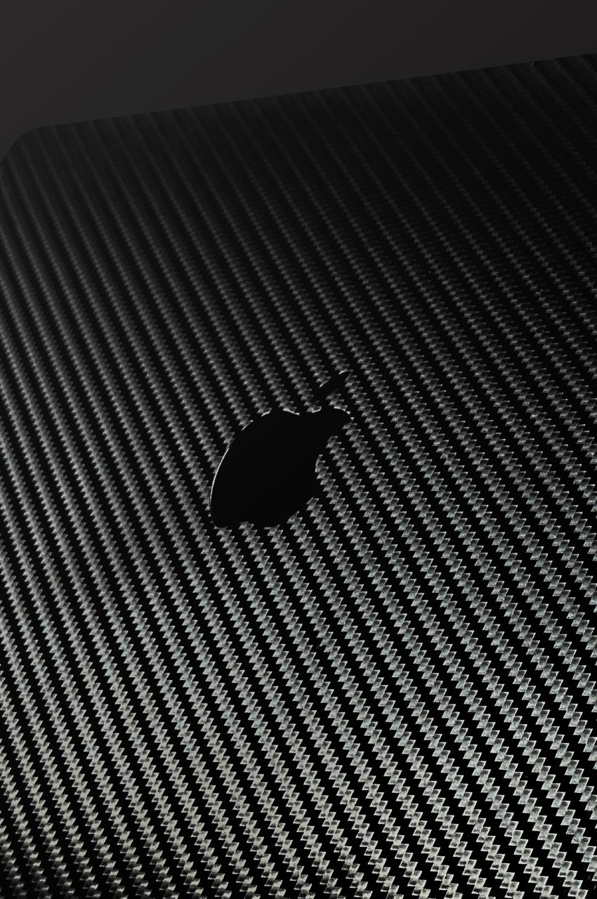 A close-up of a black carbon-fiber-textured surface on apple macbook laptop