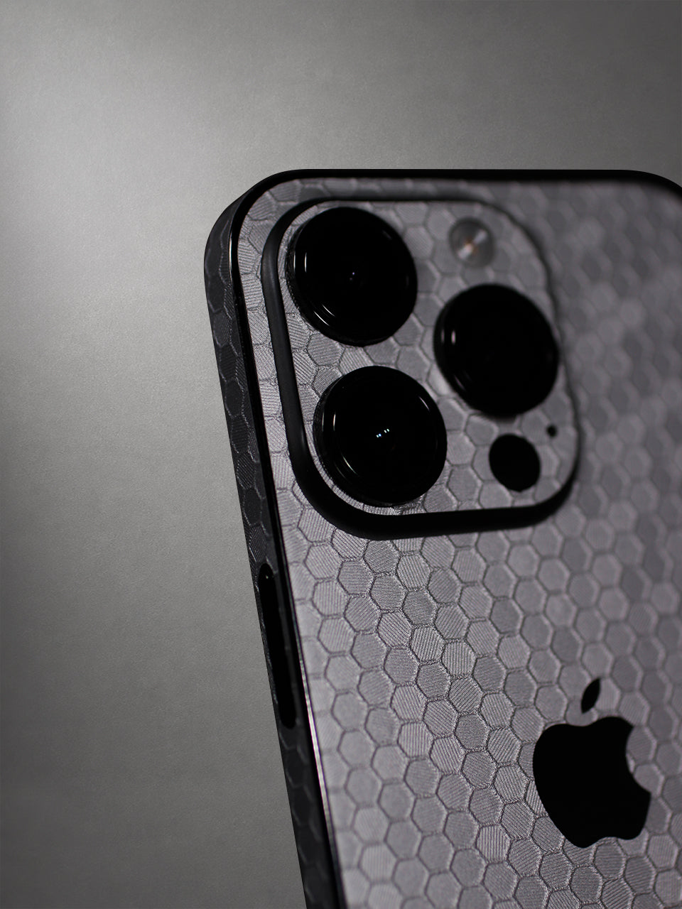 A Metallic Honeycomb-patterned iPhone Vinyl Skin photographed in a studio setting with a gray background.